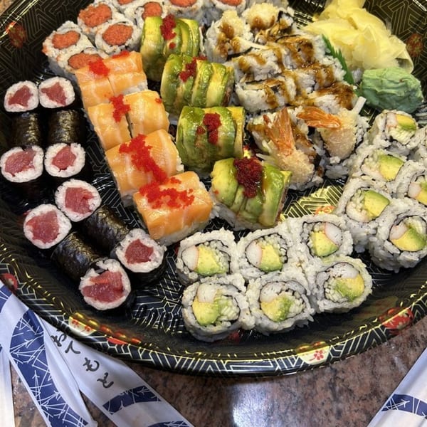 A large platter of various sushi rolls, including tuna, salmon, avocado, and shrimp.